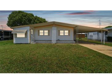 Single-wide manufactured home with carport and well-maintained lawn at 5353 Comanche St, Zephyrhills, FL 33542