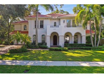 Elegant Mediterranean-style home featuring arched entryways, a balcony, and professionally landscaped grounds at 4108 W San Luis St, Tampa, FL 33629