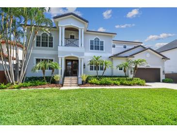 Beautiful two-story home featuring a manicured lawn and lush tropical landscaping with palm trees enhancing the curb appeal at 5013 W Leona St, Tampa, FL 33629