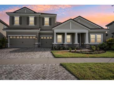 Two-story home with gray siding, a three-car garage, and a landscaped front yard at 14292 Swiss Bridge Dr, Riverview, FL 33579