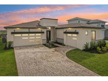 Modern two-story home featuring a three-car garage, and a brick driveway at 8320 Golden Beach Ct, Parrish, FL 34219