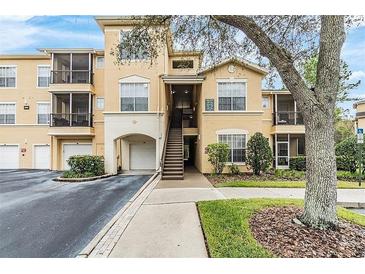 Exterior of a tan building with garages, balconies, and manicured landscaping at 5125 Palm Springs Blvd # 1303, Tampa, FL 33647