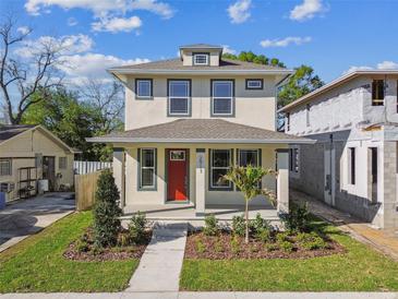 Charming two-story home with a red front door and beautifully landscaped front yard with lush green grass at 2911 W Spruce St, Tampa, FL 33607