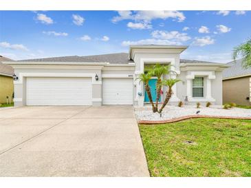Charming single-story home with a three-car garage, manicured lawn, and a bright blue front door at 6843 Boulder Run Loop, Wesley Chapel, FL 33545
