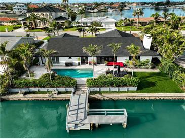 Beautiful waterfront home featuring a private dock and an inviting pool surrounded by lush landscaping at 221 Howard Dr, Belleair Beach, FL 33786