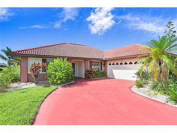 Brick home with red driveway, two car garage and lush landscaping at 1826 Wolf Laurel Dr, Sun City Center, FL 33573