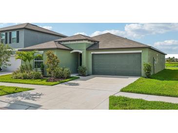 Single-story house with green exterior, two-car garage, and landscaped front yard at 13265 Great Plains Dr, Riverview, FL 33579