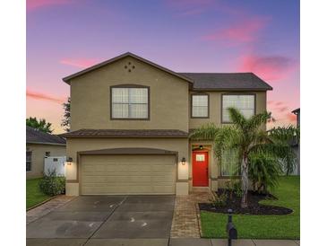 Two-story house with beige exterior, red door, and palm trees in front at 5530 Shasta Daisy Pl, Land O Lakes, FL 34639