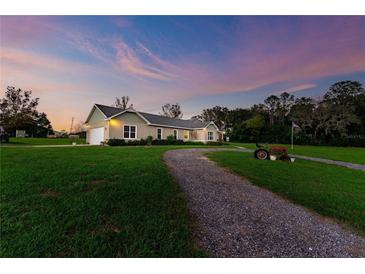 Charming house exterior with a gravel driveway and landscaping, at dusk at 36431 Florrie Mae Ln, Dade City, FL 33523