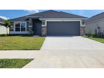 Charming single-story home showcasing a gray facade, stone accents, and a spacious two-car garage at 13260 Ogden Glade Rd, Dade City, FL 33525