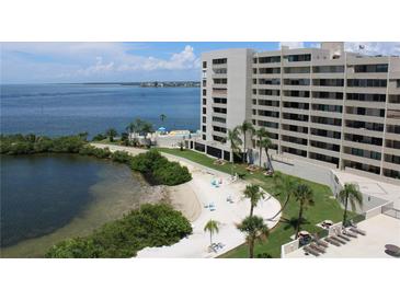Aerial view of waterfront condo building with pool, beach access, and stunning bay views at 6009 Sea Ranch Dr # 705, Hudson, FL 34667