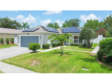 Single-story home with gray garage door and solar panels, landscaped yard at 4504 Horseshoe Pick Ln, Valrico, FL 33594