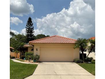 Tan house with tile roof, single car garage, and manicured lawn at 4115 Murfield E Dr, Bradenton, FL 34203