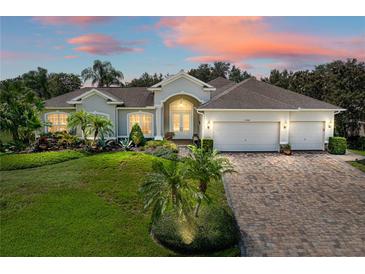 Beautiful single-story home with manicured lawn, mature landscaping, and a three-car garage at 13216 Legends Trl, Dade City, FL 33525