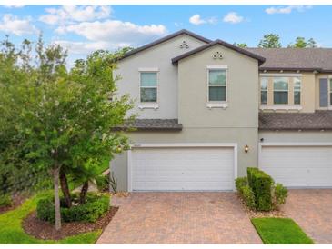 Charming townhouse with a two-car garage and brick paver driveway surrounded by lush landscaping at 10066 Corso Milano Dr, Tampa, FL 33625