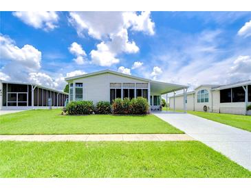 Single-wide manufactured home with carport, landscaping, and paved driveway at 6048 Ridgeway Dr, Zephyrhills, FL 33542