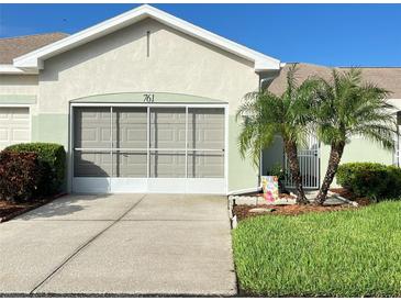 Single-car garage with a screen door and landscaping at 761 Tremont Greens Ln # 61, Sun City Center, FL 33573