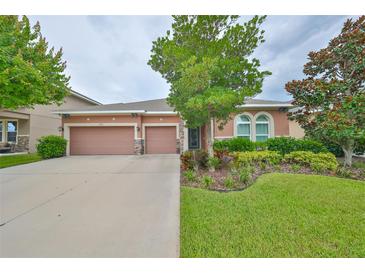 Two-story house with three-car garage and manicured lawn at 6308 Waves End Pl, Apollo Beach, FL 33572