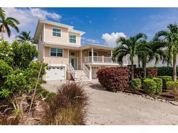 Beautiful two-story home with a beige exterior, white trim, and well-manicured landscaping with palm trees at 210 Lakeview Dr, Anna Maria, FL 34216