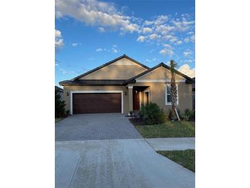 House exterior featuring a two-car garage and well-manicured landscaping at 31727 Cardinal Yard Dr, San Antonio, FL 33576