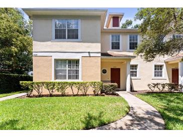 Two story townhome with red door, surrounded by lush landscaping and manicured lawn at 2080 Fiesta Ridge Ct, Tampa, FL 33604