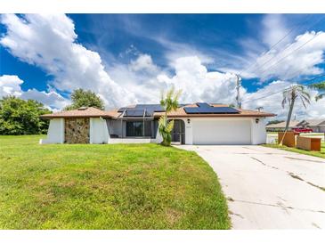 House exterior with solar panels, driveway, and well-maintained lawn at 684 Corrientes Cir, Punta Gorda, FL 33983