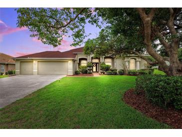 Charming single Gathering home with a well-manicured lawn, mature landscaping, and a two car garage at 13049 Thoroughbred Dr, Dade City, FL 33525