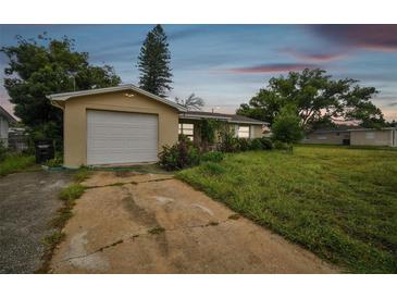 House exterior featuring a single car garage and a spacious front yard at 1240 Chelsea Ln, Holiday, FL 34691