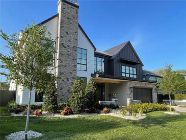 Modern two-story home with brick chimney, dark metal roof, manicured lawn and beautiful landscaping at 3305 W Beaumont St, Tampa, FL 33611