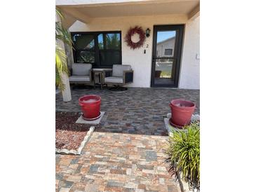 Inviting front porch with tiled flooring, two comfy chairs, and attractive landscaping at 9920 Eagles Point Cir # 2, Port Richey, FL 34668