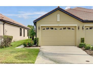 Tan villa with two-car garage, landscaping, and walkway at 227 Mystic Falls Dr, Apollo Beach, FL 33572
