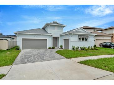 Two-story light blue house with gray double garage and paver driveway at 10520 Purple Thistle Way, San Antonio, FL 33576