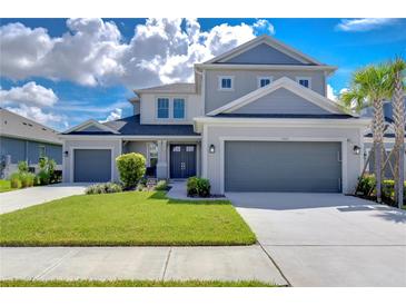 Two-story house with gray siding, two-car garage, and landscaped lawn at 2406 High Tides Way, Wesley Chapel, FL 33543