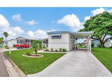 Single-wide manufactured home with carport, landscaping, and paved driveway at 122 E Saint Annes Cir, Apollo Beach, FL 33572