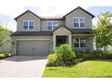 Two story home with gray siding and a three-car garage at 5776 Newberry Pines Ave, Wesley Chapel, FL 33545