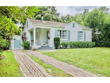 Charming bungalow with a brick driveway, lush lawn, and inviting front porch at 1411 E Powhatan Ave, Tampa, FL 33604