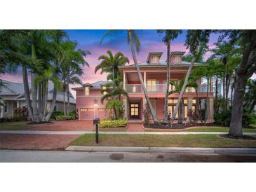 Two-story home with a pink facade, double garage and lush landscaping at 825 Islebay Dr, Apollo Beach, FL 33572
