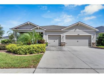 Single-story home with a three-car garage and landscaped front yard at 13012 Rain Lily Dr, Riverview, FL 33579
