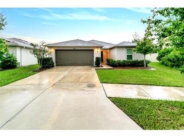 One-story home with attached garage, landscaping, and concrete driveway at 10448 Laguna Plains Dr, Riverview, FL 33578