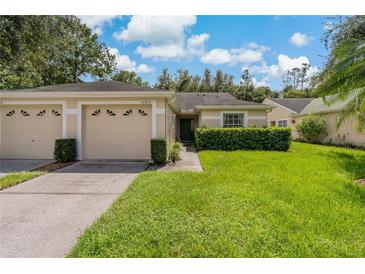 Two-car garage, light beige exterior, and well-maintained lawn at 34802 Double Eagle Ct, Zephyrhills, FL 33541