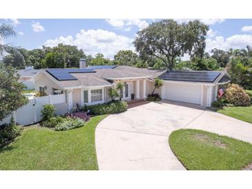 Charming single-story home featuring a circular driveway, well-manicured landscaping and solar panels at 411 Harbor View Ln, Largo, FL 33770