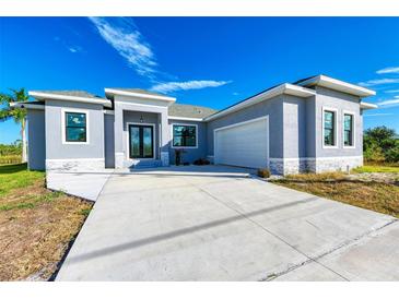 Charming single-story home features a gray exterior, well-maintained landscaping, and a spacious concrete driveway at 15154 Appleton Blvd, Port Charlotte, FL 33981