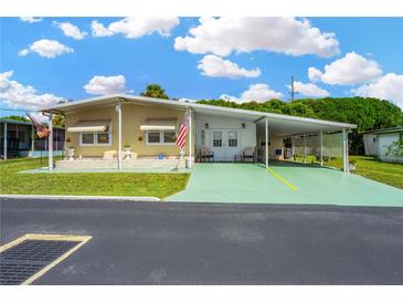 Mobile home with carport, landscaping, and American flag at 7048 El Meyers St, Zephyrhills, FL 33541