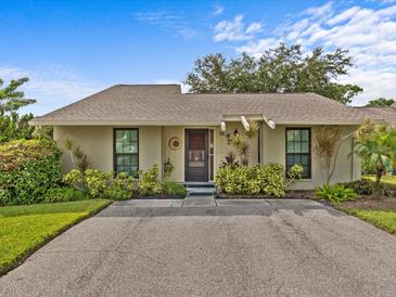 Tan house with a brown roof and lush landscaping at 30 Windrush Bay Dr, Tarpon Springs, FL 34689