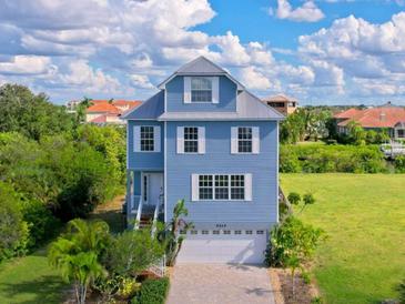 Charming three-story home features a paved driveway and a two-car garage in a serene residential setting at 6419 Marbella Blvd, Apollo Beach, FL 33572