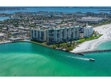 Aerial view of beachfront condo building with ocean and city views, highlighting its prime coastal location at 7100 Sunset Way # 405, St Pete Beach, FL 33706