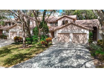 Two-story townhome with double garage and lush landscaping at 1919 Whispering Way, Tarpon Springs, FL 34689