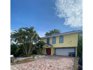 Bright yellow two-story house with a red door at 14006 Vivian Dr, Madeira Beach, FL 33708