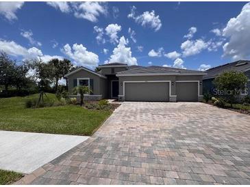 Single-story home featuring a spacious driveway, well-maintained lawn, and a 2-car garage, under a bright blue sky at 4303 Pullet Ct, Lakewood Ranch, FL 34211