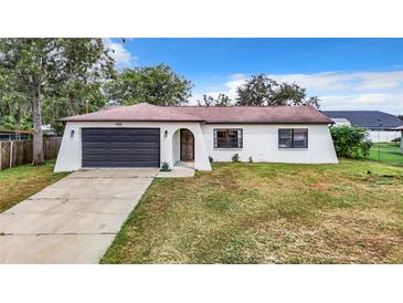 Single story home with a dark garage door and lawn at 2304 Hawthorne Rd, Spring Hill, FL 34609